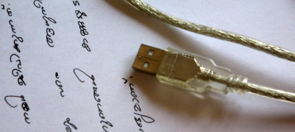 A USB cord on paper with some random words written down.